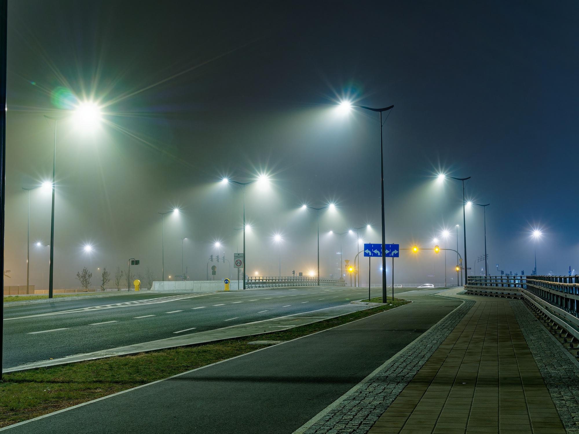 Foggy night time empty highway illuminated with street lights